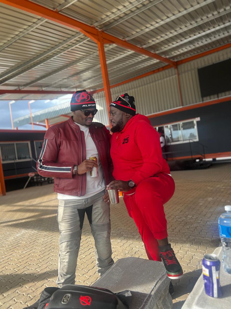Two Alpha Team members in club beanies standing under a hangar roof